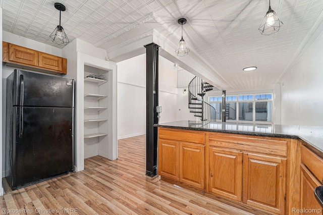 8820 Joseph Campau St Unit 2, Hamtramck, MI 48212 - kitchen with freestanding refrigerator, light wood-type flooring, brown cabinetry, pendant lighting, and dark stone counters