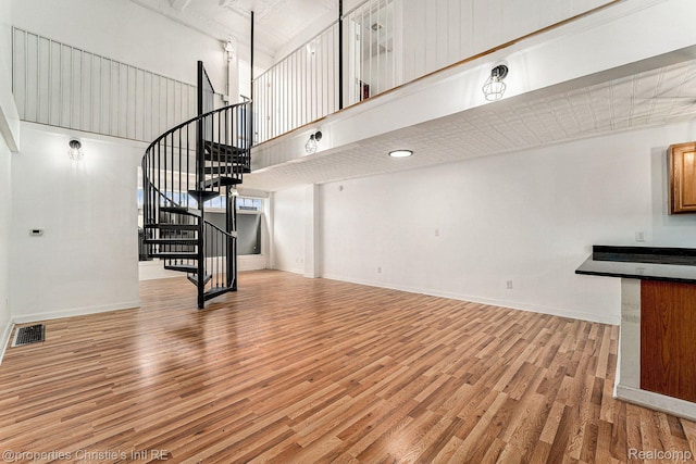 8820 Joseph Campau St Unit 2, Hamtramck, MI 48212 - unfurnished living room with a towering ceiling, light wood-style floors, stairs, and baseboards