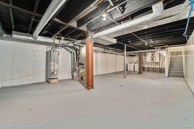 8820 Joseph Campau St Unit 2, Hamtramck, MI 48212 - unfinished below grade area featuring gas water heater, washer / dryer, heating unit, stairs, and brick wall
