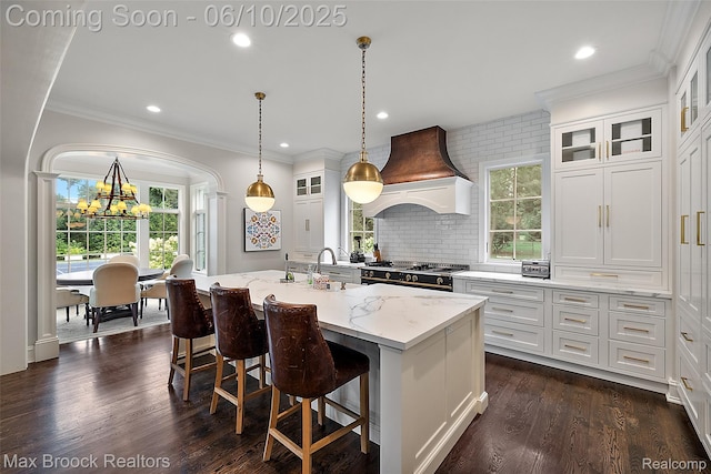 1475 Tottenham Rd, Bloomfield Hills, MI 48301 - kitchen with a chandelier, custom range hood, light stone counters, white cabinetry, and a center island with sink