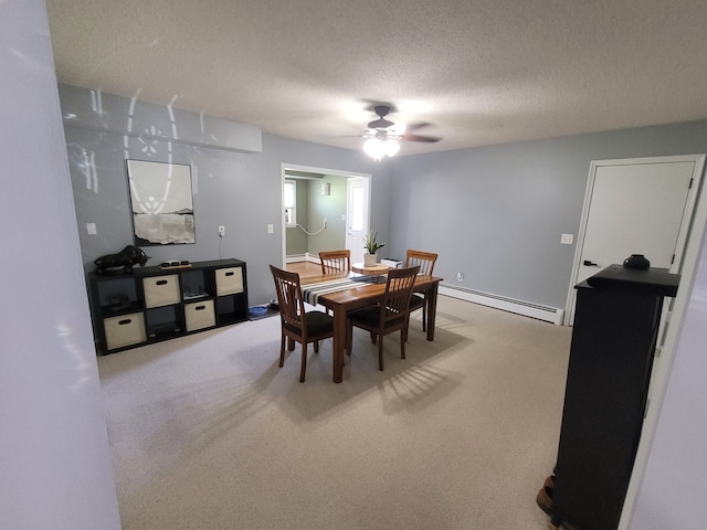 dining space with a baseboard heating unit, light carpet, ceiling fan, and a textured ceiling