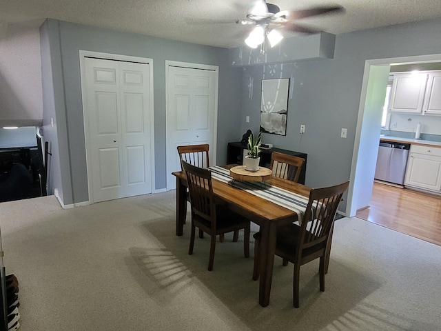 dining room featuring ceiling fan, light colored carpet, and a textured ceiling