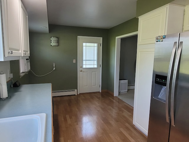 kitchen with stainless steel fridge with ice dispenser, baseboard heating, wood finished floors, and white cabinets