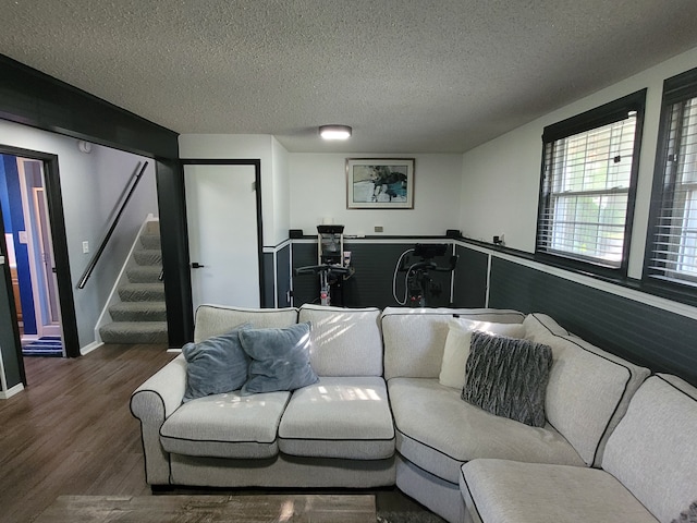 living room featuring wood finished floors, a textured ceiling, and stairs