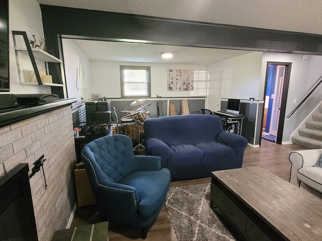 living area with wood finished floors, stairway, a fireplace, and a textured ceiling