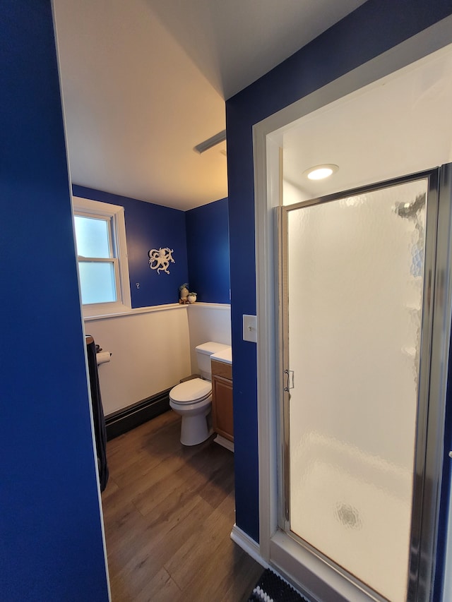 bathroom featuring wood finished floors, a stall shower, toilet, and vanity