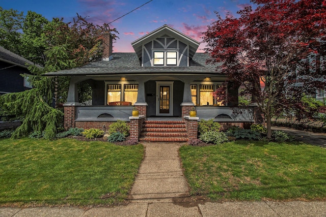 view of front of property with covered porch and a lawn