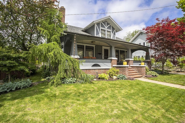 view of front facade featuring a porch, a front yard, and a chimney