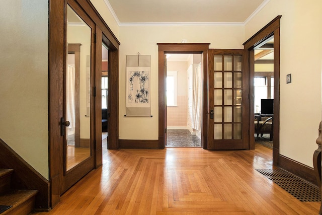 corridor with french doors, baseboards, crown molding, and light wood-style flooring