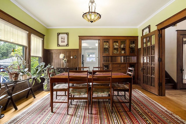 dining space featuring plenty of natural light, wainscoting, wood finished floors, and crown molding