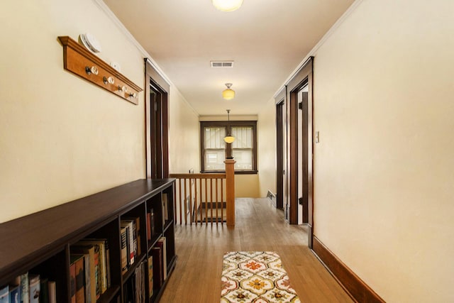 hallway with wood finished floors, an upstairs landing, and ornamental molding