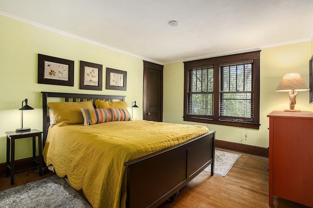 bedroom featuring wood finished floors, baseboards, and crown molding
