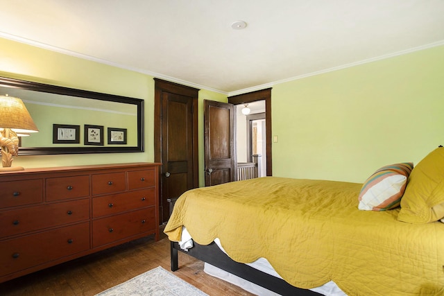 bedroom with dark wood finished floors and crown molding