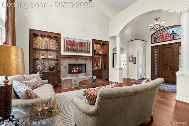 4563 Haverhill, Commerce Twp, MI 48382 - living room with arched walkways, decorative columns, wood finished floors, a premium fireplace, and high vaulted ceiling