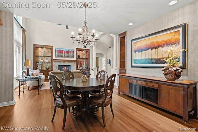 4563 Haverhill, Commerce Twp, MI 48382 - dining room with arched walkways, ornate columns, a warm lit fireplace, wallpapered walls, and wood finished floors