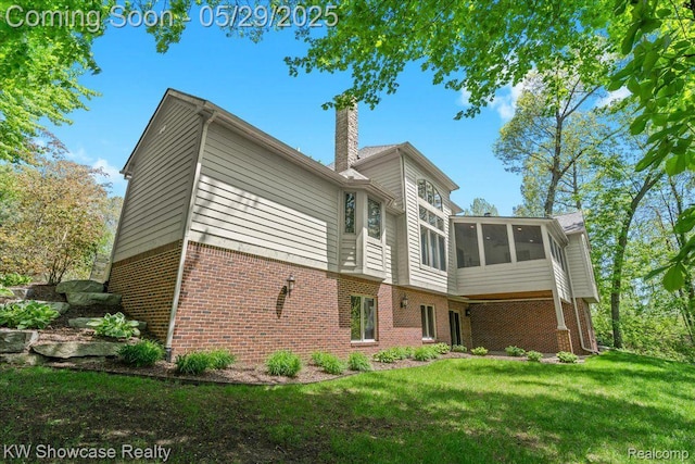 4563 Haverhill, Commerce Twp, MI 48382 - rear view of house with brick siding, a sunroom, a chimney, and a lawn