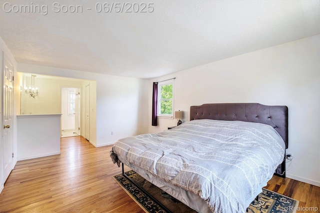 4371 E Cook Rd, Grand Blanc, MI 48439 - bedroom featuring a chandelier, wood finished floors, and baseboards