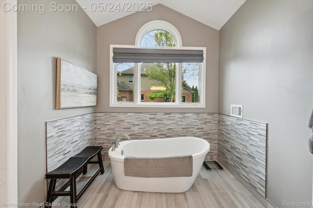 921 Gleneagles, Highland, MI 48357 - bathroom with tile walls, a freestanding bath, vaulted ceiling, and wainscoting