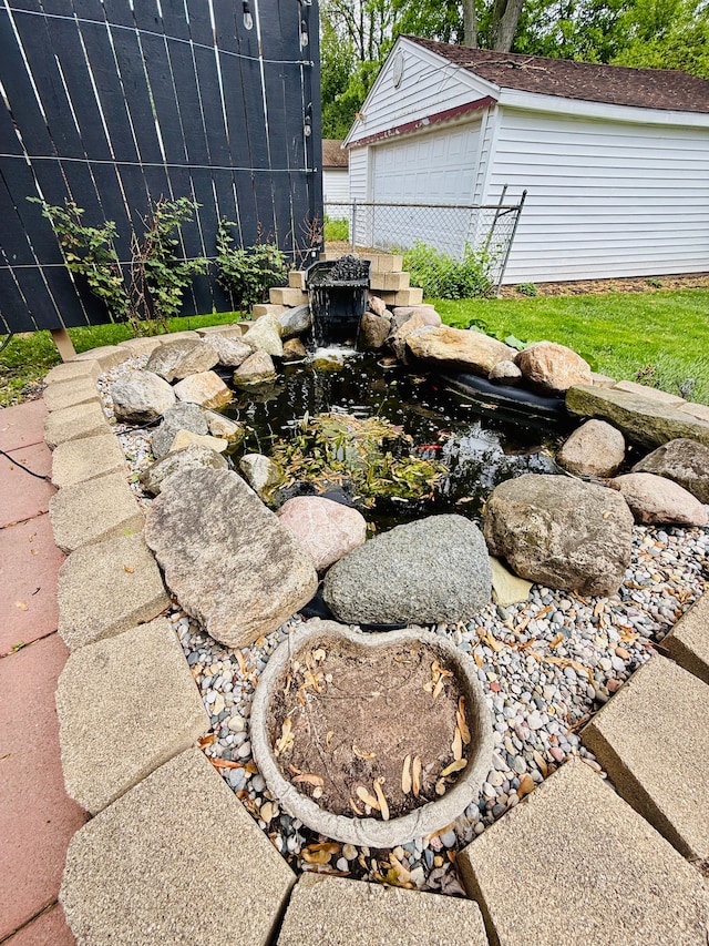 992 Key W Dr, Clawson, MI 48017 - view of patio / terrace featuring a garden pond, fence, an outbuilding, and a garage