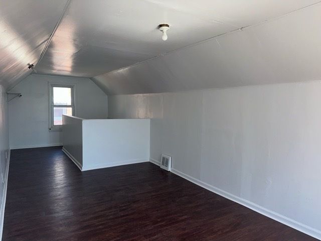 1688 S Ethel St, Detroit, MI 48217 - additional living space with vaulted ceiling, dark wood-style floors, and baseboards