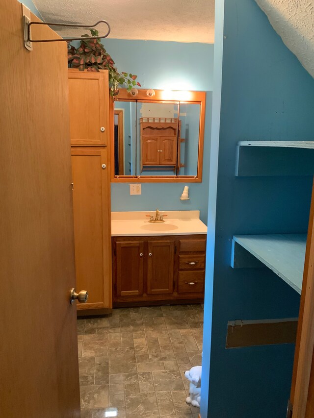 1483 W Bear Lake Rd NE, Kalkaska, MI 49646 - bathroom featuring a textured ceiling, vanity, and stone finish floors