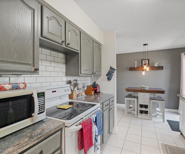 11589 Owosso Rd, Fowlerville, MI 48836 - kitchen with white appliances, decorative backsplash, light tile patterned flooring, baseboards, and a textured ceiling
