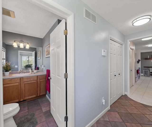 11589 Owosso Rd, Fowlerville, MI 48836 - bathroom featuring a textured ceiling, vanity, toilet, baseboards, and a closet