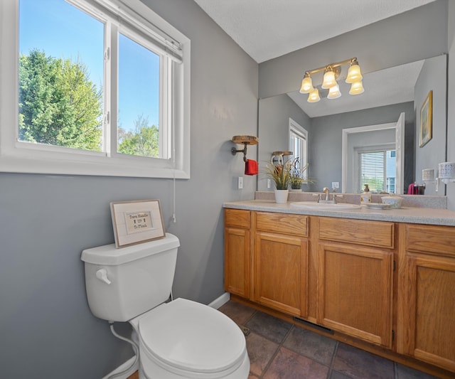 11589 Owosso Rd, Fowlerville, MI 48836 - bathroom with toilet, vanity, baseboards, and a chandelier