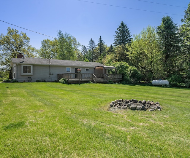 11589 Owosso Rd, Fowlerville, MI 48836 - view of grassy yard featuring a wooden deck and an outdoor fire pit