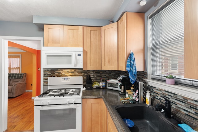 2270 23rd St, Wyandotte, MI 48192 - kitchen with white appliances, light brown cabinetry, a sink, dark countertops, and tasteful backsplash