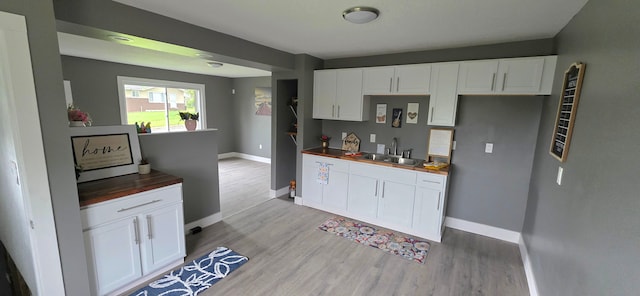 6241 Bermuda Ln, Mount Morris, MI 48458 - kitchen with a sink, baseboards, light wood-style flooring, and white cabinetry