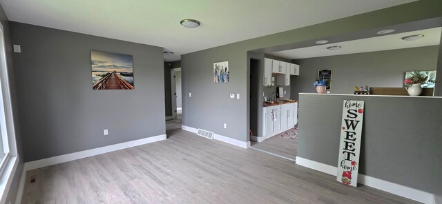 6241 Bermuda Ln, Mount Morris, MI 48458 - kitchen featuring white cabinets, light wood-style flooring, baseboards, and a sink