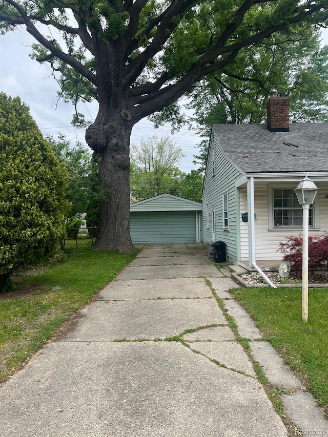 20711 Gaukler St, Saint Clair Shores, MI 48080 - view of side of property with a chimney, a detached garage, roof with shingles, and a lawn