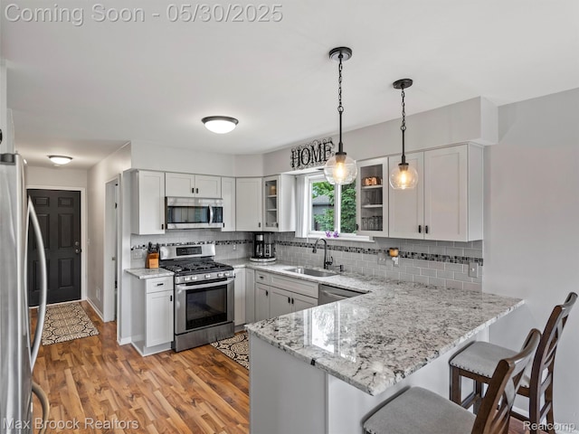 6102 Cherry Ridge Dr, Howell, MI 48855 - kitchen featuring stainless steel appliances, a sink, a peninsula, decorative backsplash, and glass insert cabinets