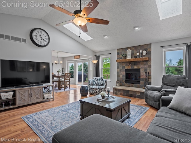 6102 Cherry Ridge Dr, Howell, MI 48855 - living area with a skylight, a textured ceiling, lofted ceiling, a large fireplace, and a chandelier
