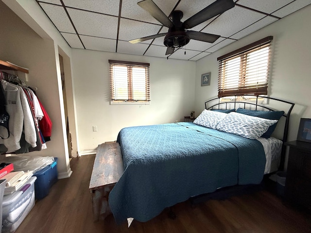 bedroom featuring wood finished floors, a paneled ceiling, baseboards, and a ceiling fan
