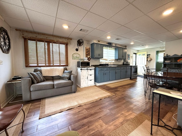 living area with dark wood-style floors, a paneled ceiling, and baseboards