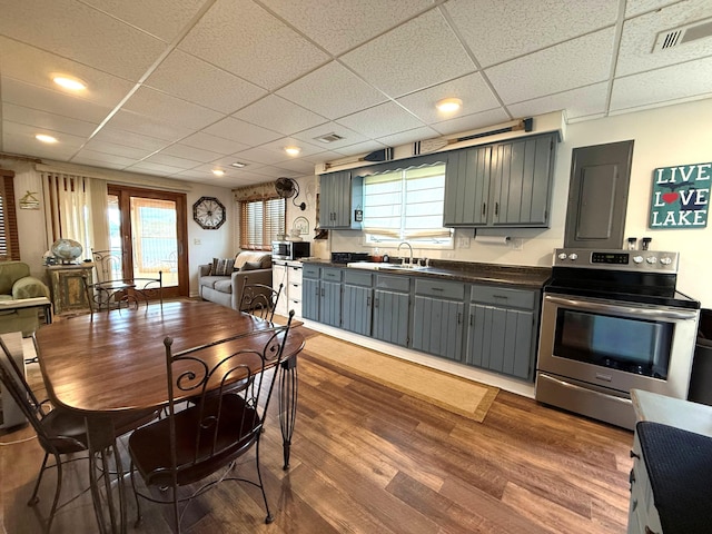 kitchen with appliances with stainless steel finishes, dark countertops, gray cabinetry, wood finished floors, and open floor plan