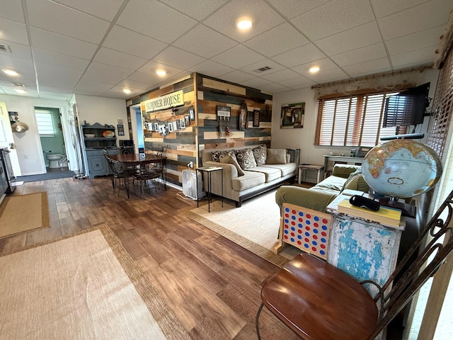 living area with a paneled ceiling and wood finished floors