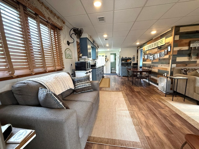 living area with dark wood-style flooring, a drop ceiling, and recessed lighting