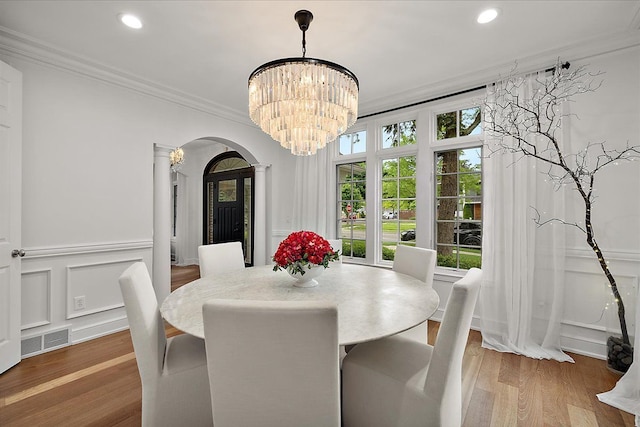 820 Hazel St, Birmingham, MI 48009 - dining area with arched walkways, ornamental molding, a chandelier, wood finished floors, and a decorative wall
