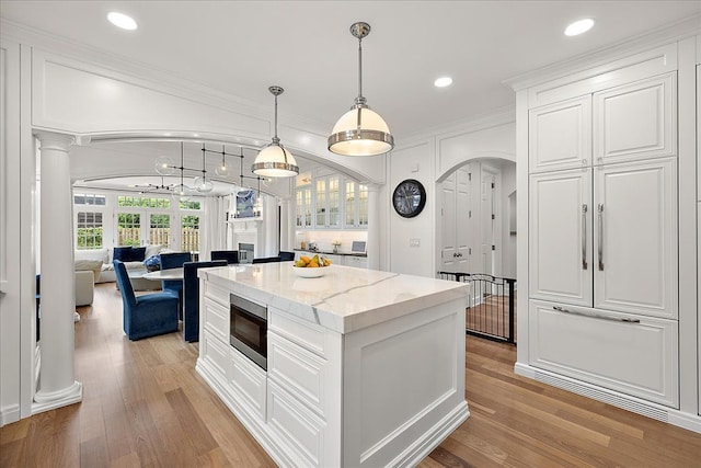 820 Hazel St, Birmingham, MI 48009 - kitchen featuring stainless steel microwave, white cabinetry, arched walkways, light wood-style flooring, and recessed lighting