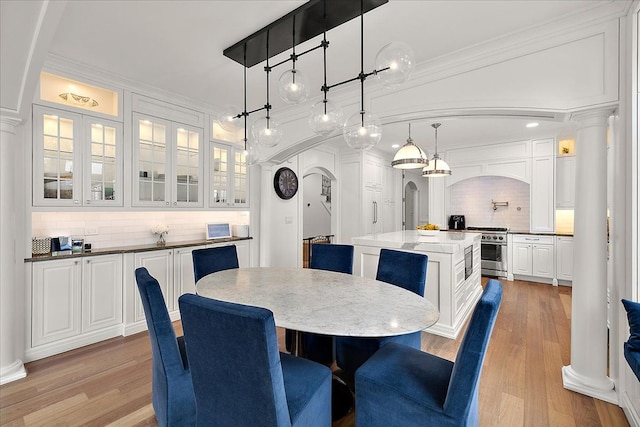 820 Hazel St, Birmingham, MI 48009 - dining room featuring arched walkways, ornate columns, light wood finished floors, and ornamental molding