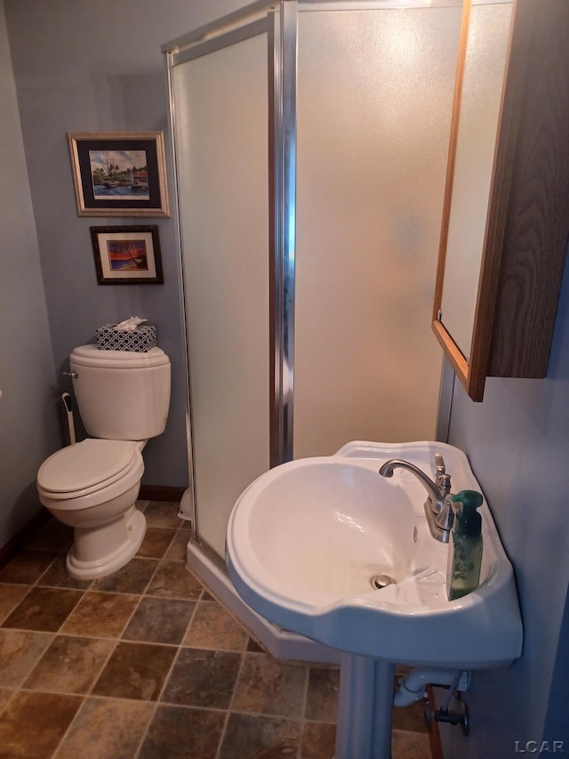 1186 Buckingham Ct, Adrian, MI 49221 - bathroom with baseboards, a stall shower, toilet, stone finish flooring, and a sink