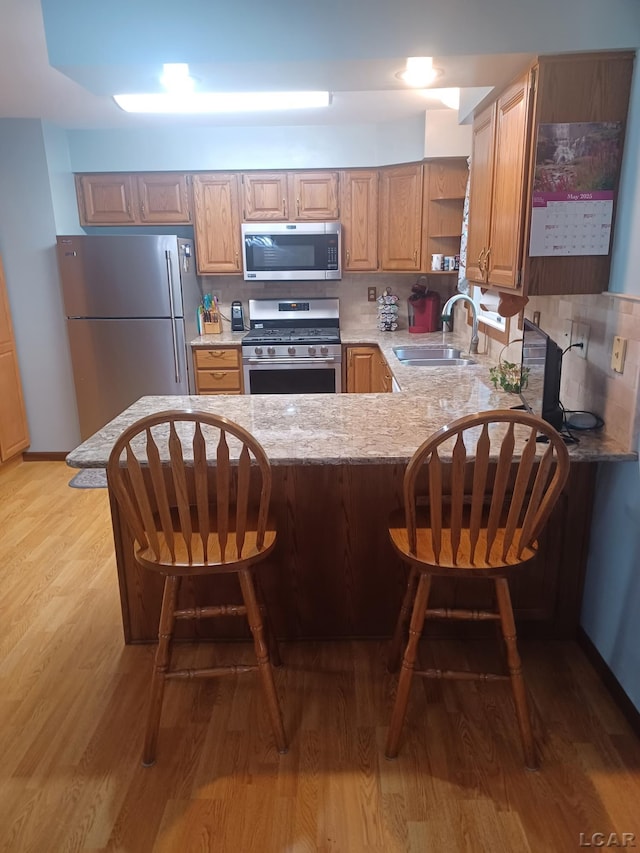 1186 Buckingham Ct, Adrian, MI 49221 - kitchen with stainless steel appliances, a sink, open shelves, light wood-type flooring, and a peninsula