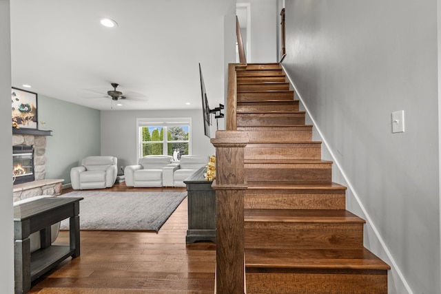1600 Tuttle Rd, Mason, MI 48854 - stairway with wood finished floors, a ceiling fan, a stone fireplace, recessed lighting, and baseboards