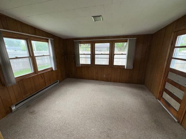 175 S Hudnut, Barryton, MI 49305 - empty room with a baseboard heating unit, wood walls, and light colored carpet