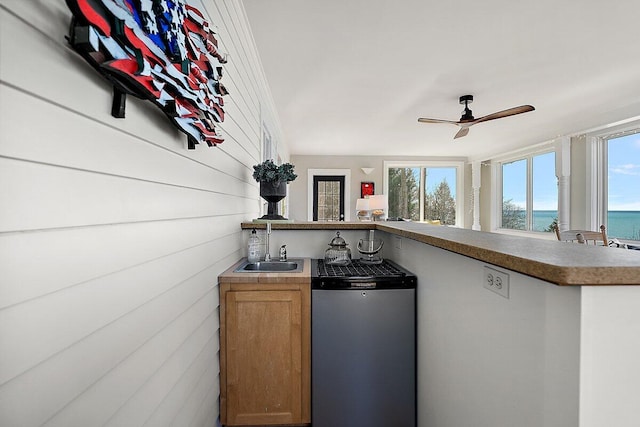 8282 W Harrison Rd, Mears, MI 49436 - kitchen featuring refrigerator, ceiling fan, a water view, a sink, and a peninsula