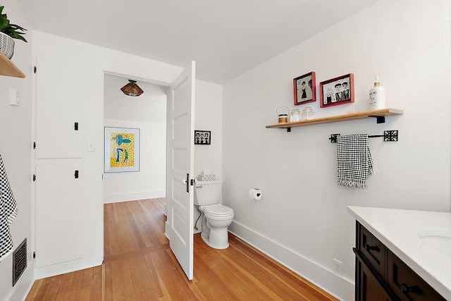 8282 W Harrison Rd, Mears, MI 49436 - bathroom featuring wood finished floors, toilet, vanity, and baseboards