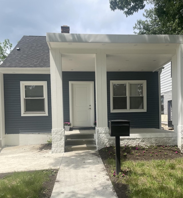 8841 Auburn St, Detroit, MI 48228 - view of exterior entry featuring a chimney, a shingled roof, and a porch